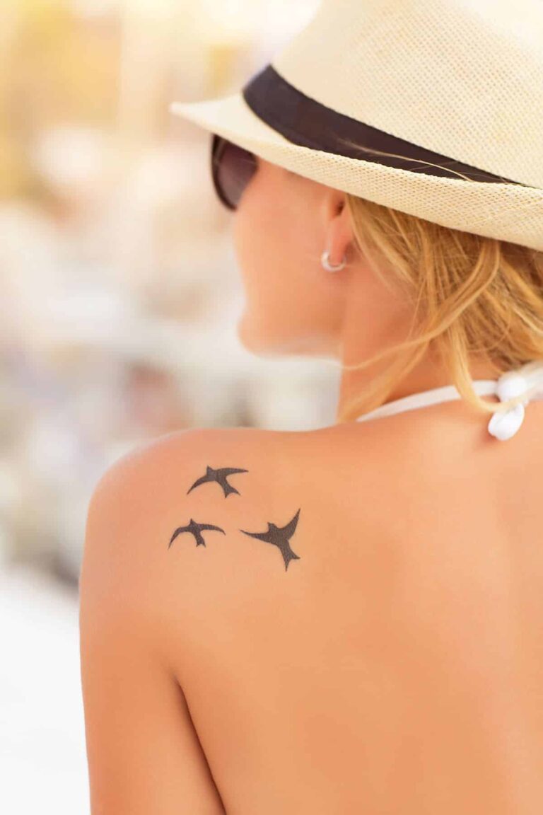 Tatouage minimaliste sur le haut du dos d'une femme, parfait pour une touche discrète et élégante.