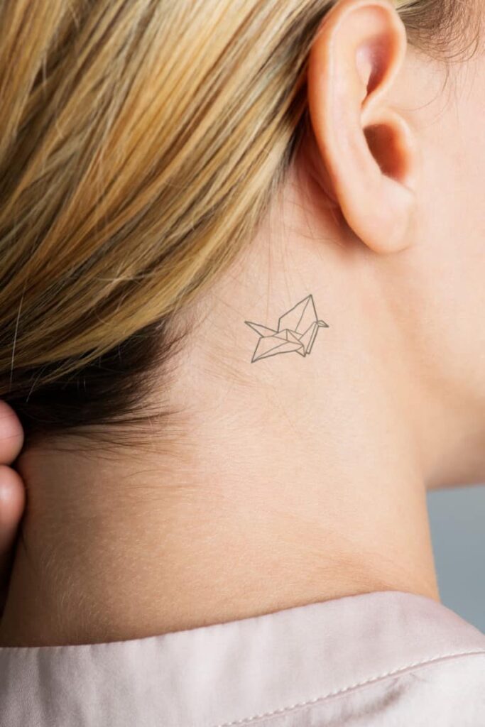 Tatouage délicat derrière l'oreille avec signification symbolique