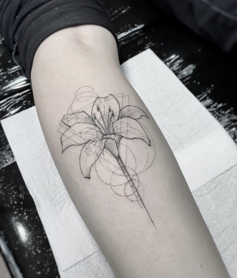 Tatouage fleur de lys détaillé en noir et gris sur l'avant-bras, symbole d'élégance et de royauté