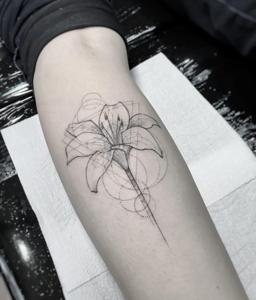 Tatouage fleur de lys détaillé en noir et gris sur l'avant-bras, symbole d'élégance et de royauté
