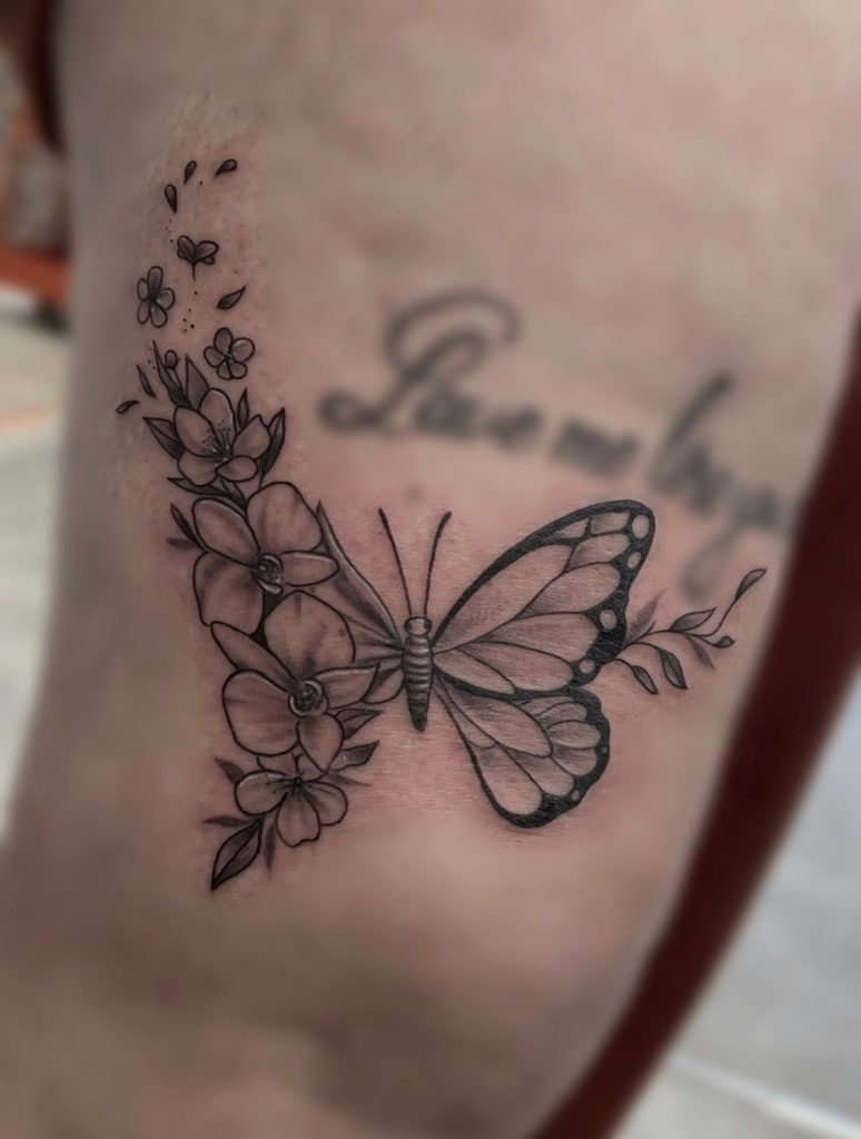 Tatouage papillon aux motifs floraux symbolisant la beauté et la transformation